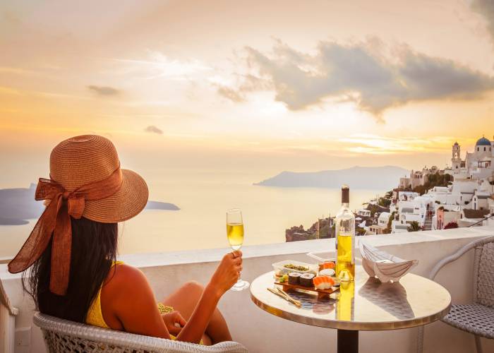 Girl drinking wine with view of Santorini Littleaom shutterstock